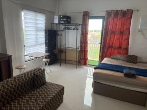 a bedroom with a bed and a couch and a window at Studio condo oceanside - pools, gym, mini market in Dao +18 photos