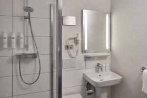 a white bathroom with a shower and a sink at Four Points Flex by Sheraton Kiel in Kiel +25 photos