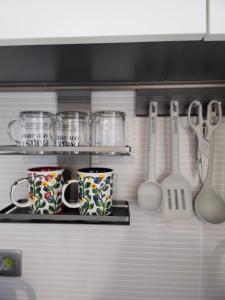 two cups and utensils on a shelf in a kitchen at 히얼마리나 in Ungch'ŏn-ni