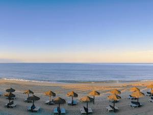 a group of umbrellas and chairs on a beach at Hotel Quinta do Lago in Quinta do Lago