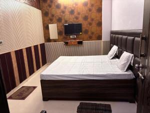 a small bedroom with a bed and a tv at Absolute hostel in Meerut