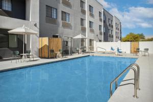 a large swimming pool with chairs and umbrellas next to a building at Spark By Hilton Tucson Airport in Tucson
