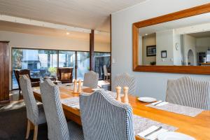 a dining room with a table and chairs and a mirror at Hidden Lodge Queenstown in Queenstown