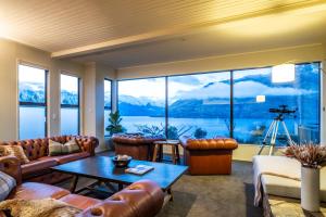 a living room with leather furniture and a large window at Hidden Lodge Queenstown in Queenstown