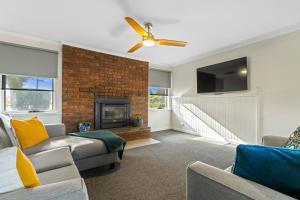 a living room with a brick fireplace and a ceiling fan at Anchor Wheel Motel in St Helens
