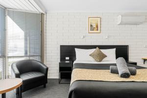 a bedroom with a bed and a chair at Anchor Wheel Motel in St Helens