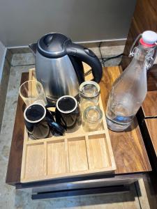 a tea kettle and cups on a wooden tray on a table at Lawn Side Manor in Jhājra
