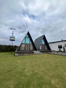 a building with a pointed roof on a grass field at Lawn Side Manor in Jhājra