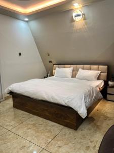 a bedroom with a large bed with white sheets at Lawn Side Manor in Jhājra