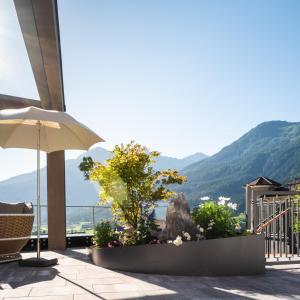 a patio with an umbrella and mountains in the background at Hotel Gassner - 4 Sterne Superior - 1200 qm SPA in Neukirchen am Großvenediger