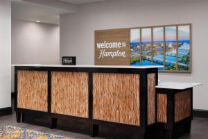 a reception desk in a lobby with a sign on the wall at Hampton Inn Augusta Fort Eisenhower in Augusta