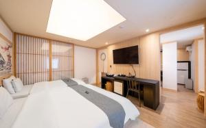a bedroom with a white bed and a flat screen tv at Daeheung Manwol Hotel in Daejeon