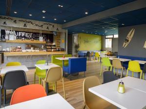 a restaurant with white tables and colorful chairs at ibis budget Toulouse Centre Gare in Toulouse