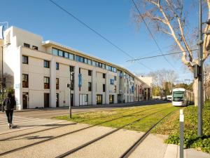 a train is on a street next to a building at ibis budget Avignon Centre in Avignon