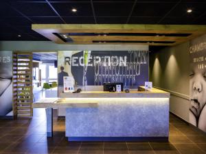 a reception counter in a room with posters on the wall at ibis budget Quimper in Quimper