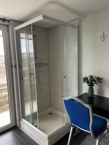 a glass shower with a blue chair next to a desk at Fuldablick in Melsungen +19 photos