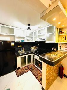 a kitchen with white cabinets and black appliances at Calapan Transient House Xevera in Calapan