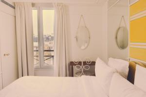 a white bedroom with a bed and a window at Hôtel Blanca - Orso Hotels in Paris +40 photos