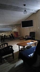 a living room with a table and chairs and a tv at Le grenier in Bazas