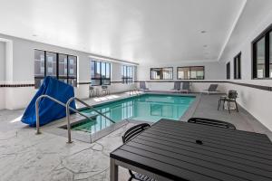 a large swimming pool with a table and chairs at Spark by Hilton Shawnee in Shawnee
