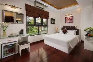 a white bedroom with a large white bed and windows at Hanoi TrangTrang Hotel in Hanoi