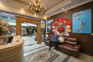a man and woman sitting on a couch in a lobby at Hanoi TrangTrang Hotel in Hanoi