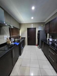 a large kitchen with black cabinets and a white tile floor at Paradise View Apartment in Gatunga