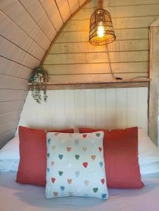 a bed with two red pillows and a lamp at Tan-y-Dderwen Pod in Machynlleth