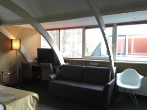 Habitación con sofá, mesa y ventanas. en Golden Mansion Aparthotel, en Ámsterdam