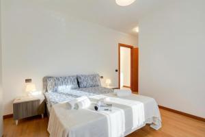 a white bedroom with a bed and a mirror at Magnolia: Laveno Centre 2BR with Terrace - Happy Rentals in Laveno-Mombello