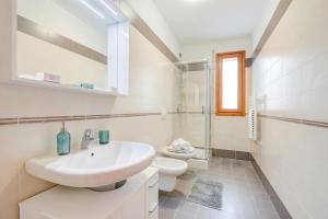 a white bathroom with a sink and a toilet at Magnolia: Laveno Centre 2BR with Terrace - Happy Rentals in Laveno-Mombello