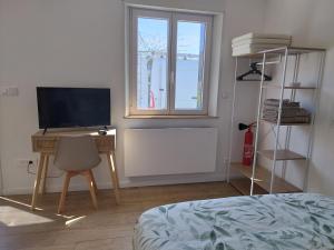 a bedroom with a desk with a television and a window at Studio de Marie in Bordeaux-Saint-Clair