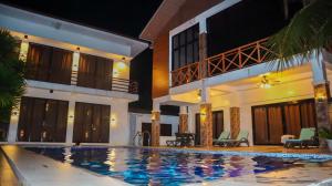 a villa with a swimming pool at night at The Lei's Hotel and Beach Resort in Mercedes