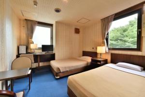a hotel room with two beds and a desk at Hotel Kangetsuso in Tokyo