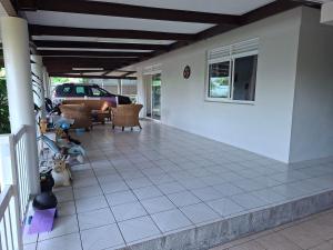 a porch of a house with chairs and a car at Maison Tahiti in Paea