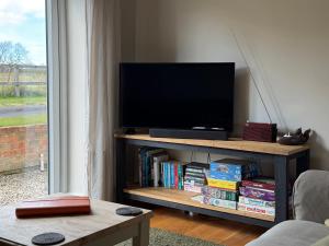 a flat screen tv on a book shelf with books at The Old Garage in Rural Northumberland in Edlingham