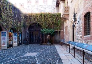 an alley with benches in front of a building with ivy at Italianflat - Palazzo Rizzardi in Verona