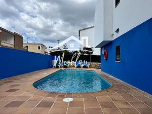 a swimming pool with chairs and a blue wall at Sa Torreta 3 in Cala Blanca