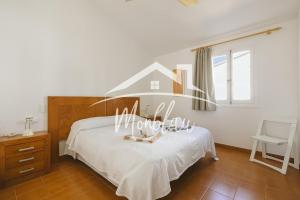 a bedroom with a white bed with a house sign on it at Sa Torreta 3 in Cala Blanca +15 photos