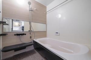 a bathroom with a bath tub and a mirror at ZABOCON Honcho Terrace in Sapporo +1 photo