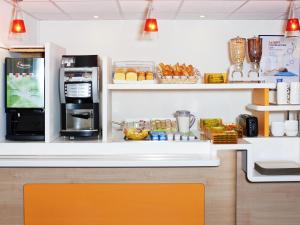 a kitchen with a counter with a microwave and a refrigerator at ibis budget Orgeval in Orgeval