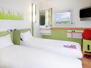 a hotel room with two beds and a window at ibis budget Orgeval in Orgeval +34 photos