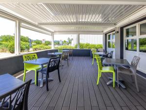 a covered deck with tables and chairs and windows at Ibis Budget Montelimar in Montélimar