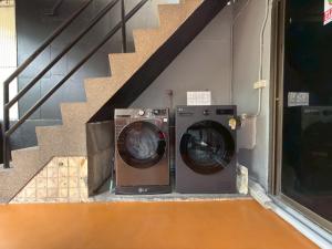 a washing machine and a dryer sitting under a staircase at Merge Hostel Chinatown in Samphanthawong