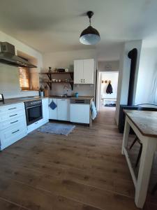 a kitchen with white cabinets and a wooden floor at Chalupa ve Svinné in Svinná +8 photos