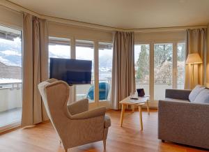 a living room with a couch and a tv at Seehotel Riviera at Lake Lucerne in Gersau