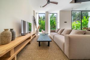 a living room with a couch and a tv at Lily Villas - Rice Field Views Escape with Private Pool in Canggu