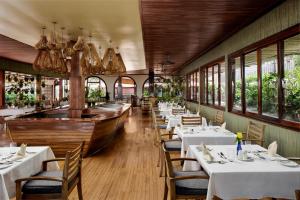 a restaurant with white tables and chairs and windows at Constellation Apartments in Kampala