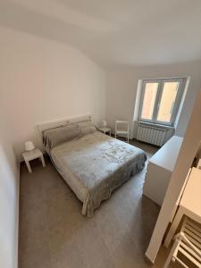 ein weißes Schlafzimmer mit einem Bett und zwei Fenstern in der Unterkunft Cielo in Mele