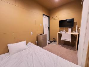 a bedroom with a bed and a desk and a computer at NikkaHotel東郷店 in Togo